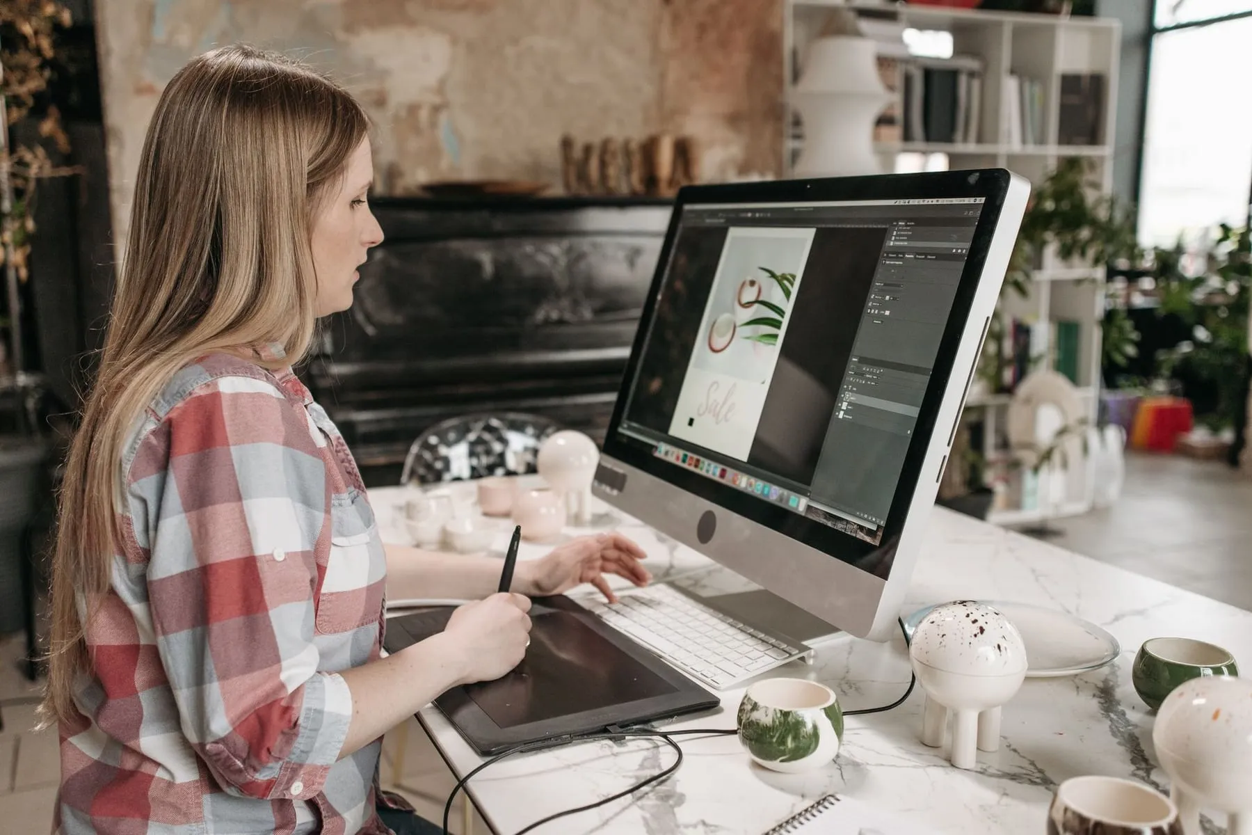 Designer desenhando em uma mesa digitalizadora em frente ao computador