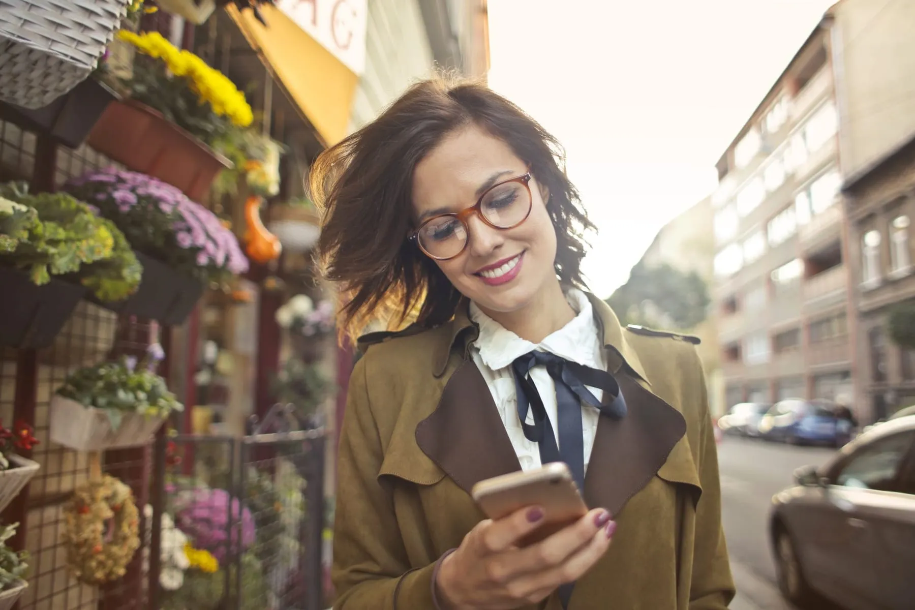 Comerciante usando o smartphone em frente à própria floricultura