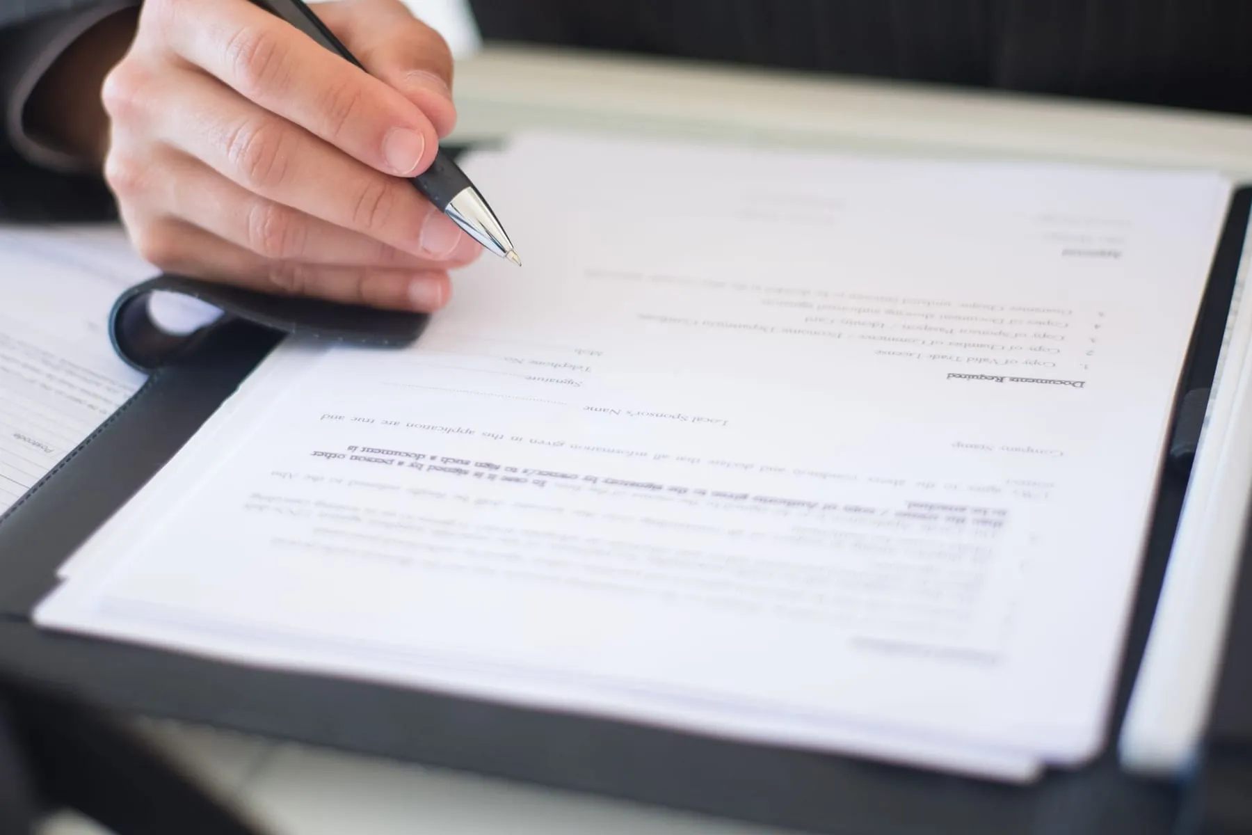 Mão assinando um documento oficial sobre a mesa