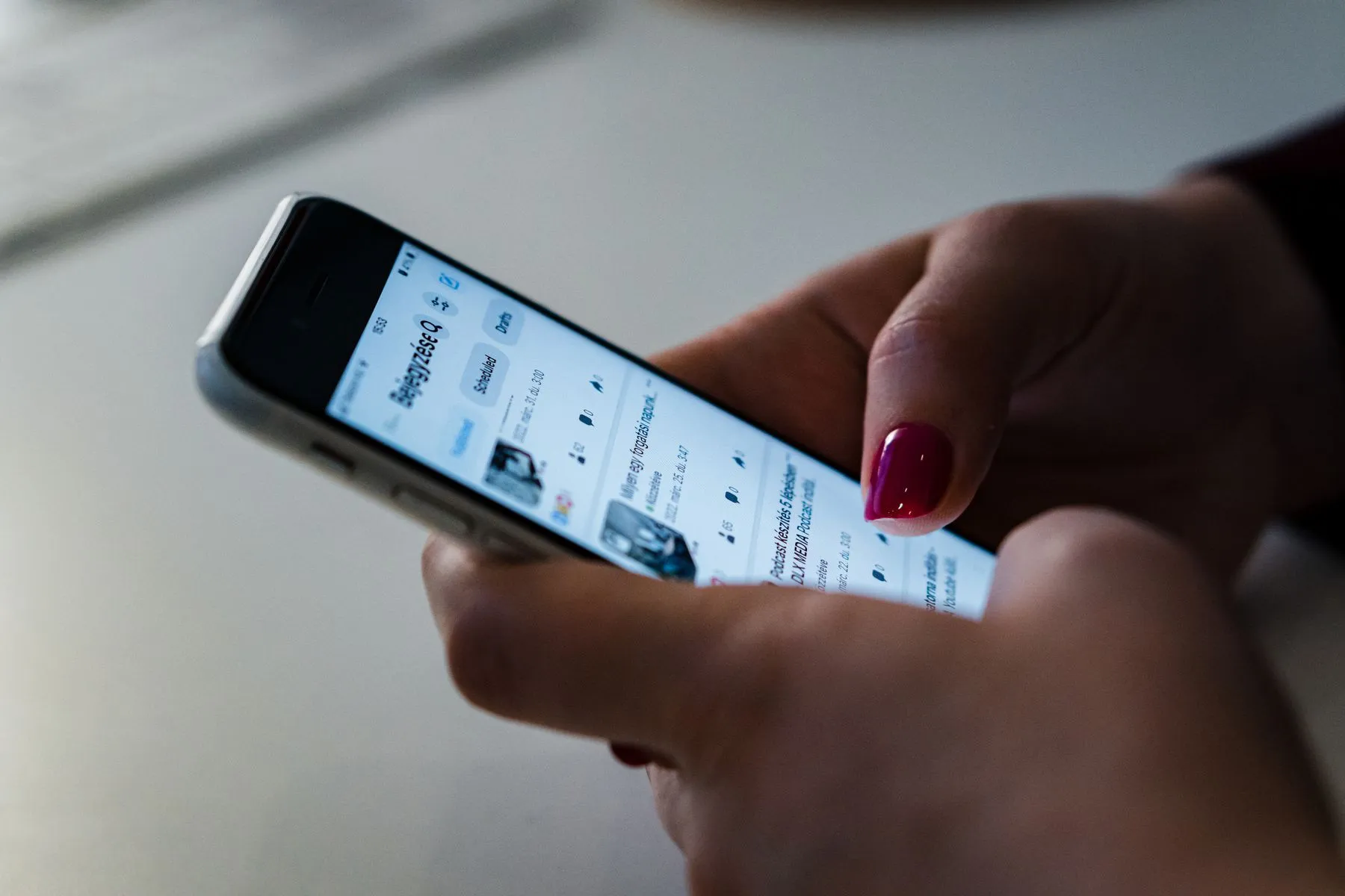 Mão segurando um smartphone com um feed de anúncios aberto